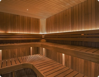 A sauna clad in vertical panelling with a long bench run under a low ceiling